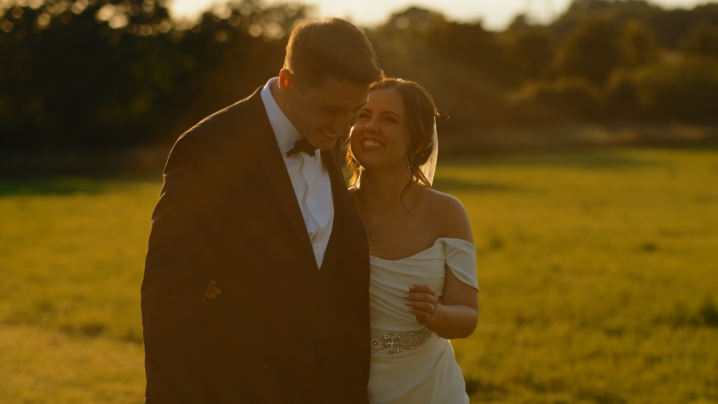 Couple smiling at each other outside The Little Green Wedding Barn captured by a Norfolk wedding videographer