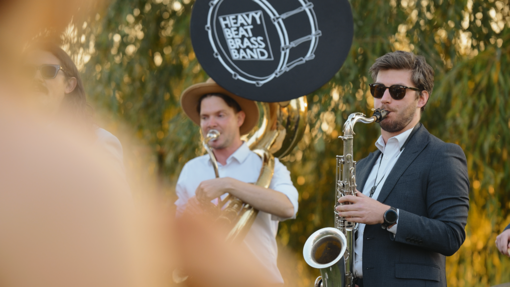 brass band playing outside the The Little Green Wedding Barn at golden hour captured by a Norfolk wedding videographer