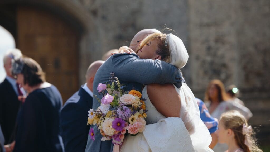 Guest hugging bride at pentney abbey wedding reception