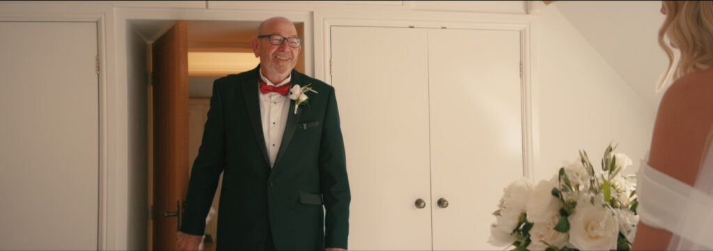 father of the bride smiling at bride for first look in her dress