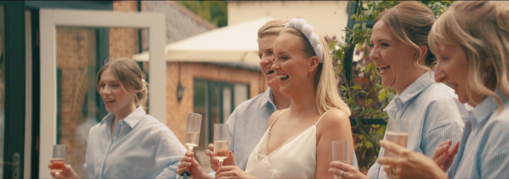 bride and bridal party laughing at their wedding at curds hall barn in norfolk