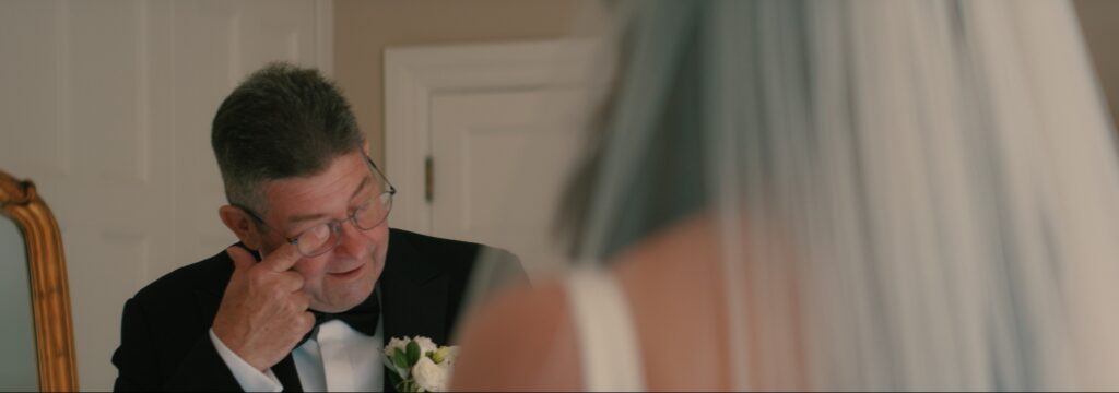 Father of the bride wiping away a tear during first look at bride during Reymerston Hall Norfolk Wedding